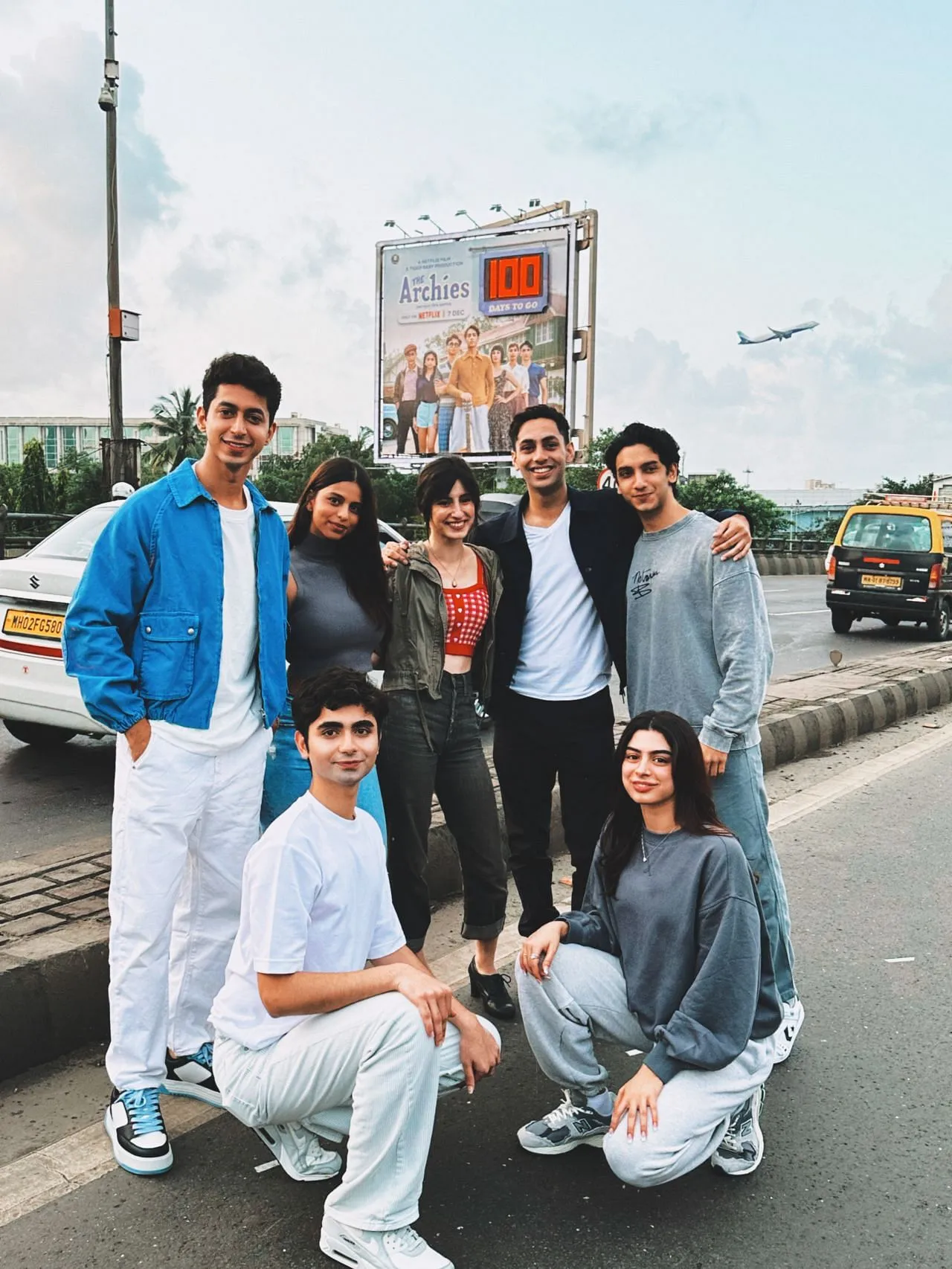 The cast posing with the billboard  