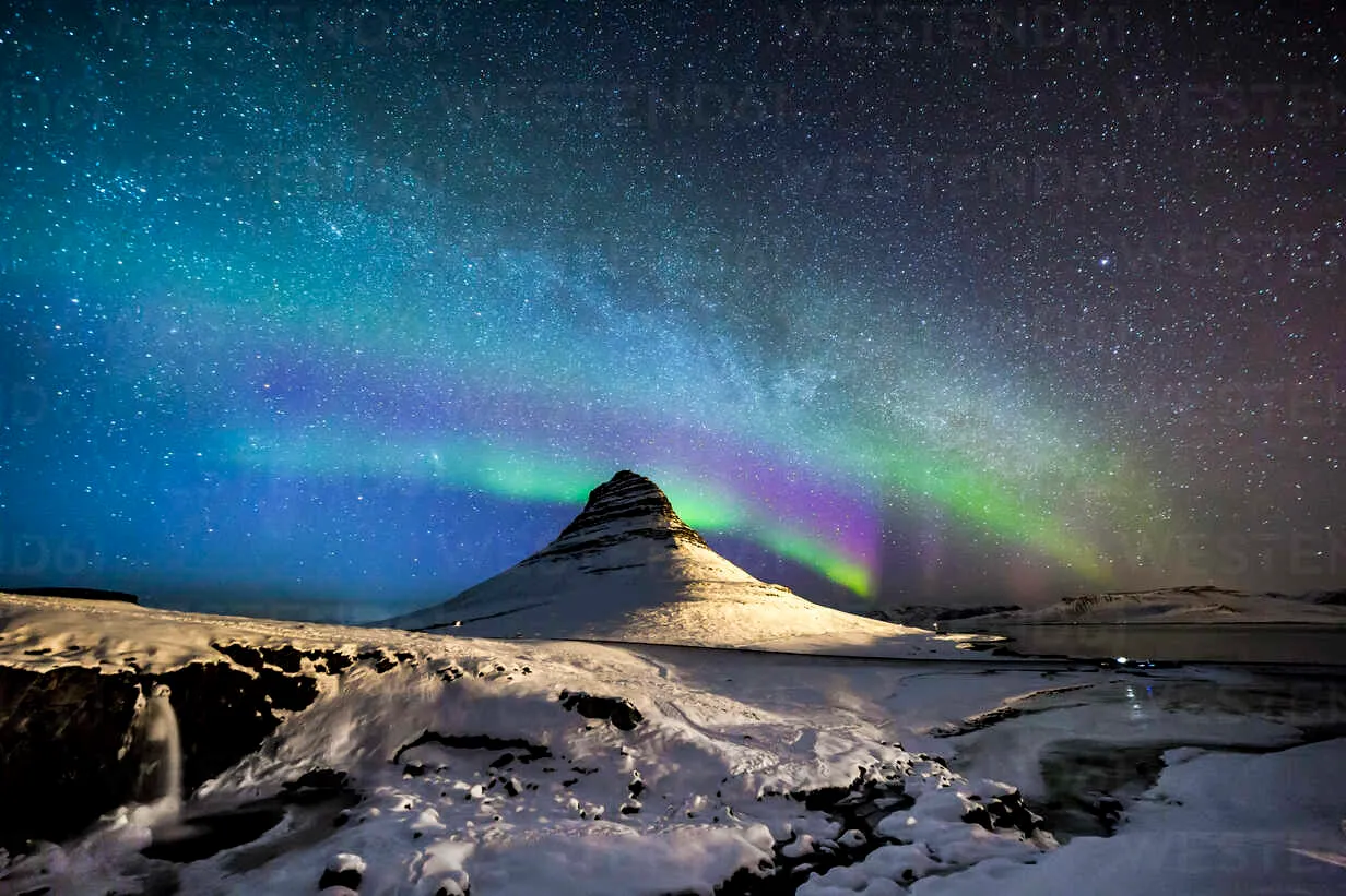 Amazing view of aurora borealis glowing in night sky with stars over  mountain covered with snow in winter in Iceland stock photo