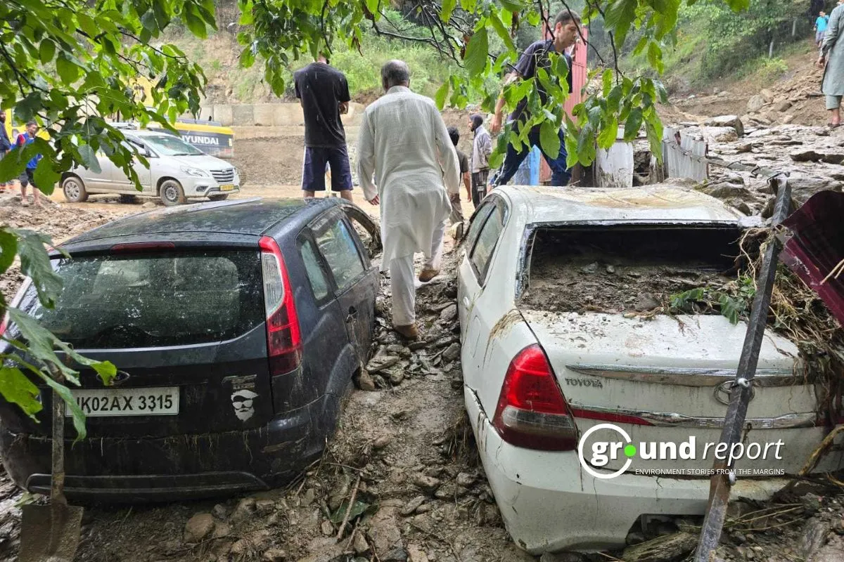 Residents inspect the damage caused by a recent landslide, which buried several vehicles under debris and mud