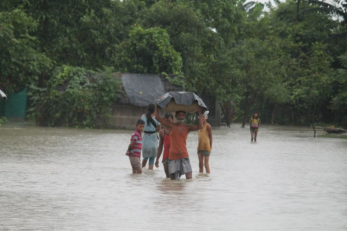 People wade through knee-deep water with their belongings