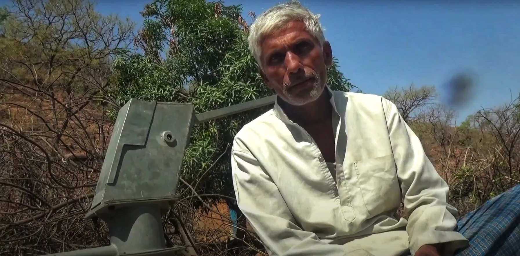 Vrindavan, a resident of Machora sitting in front of a non-functional hand pump