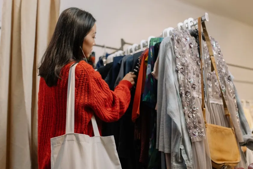 A woman looks at clothing on a rack	