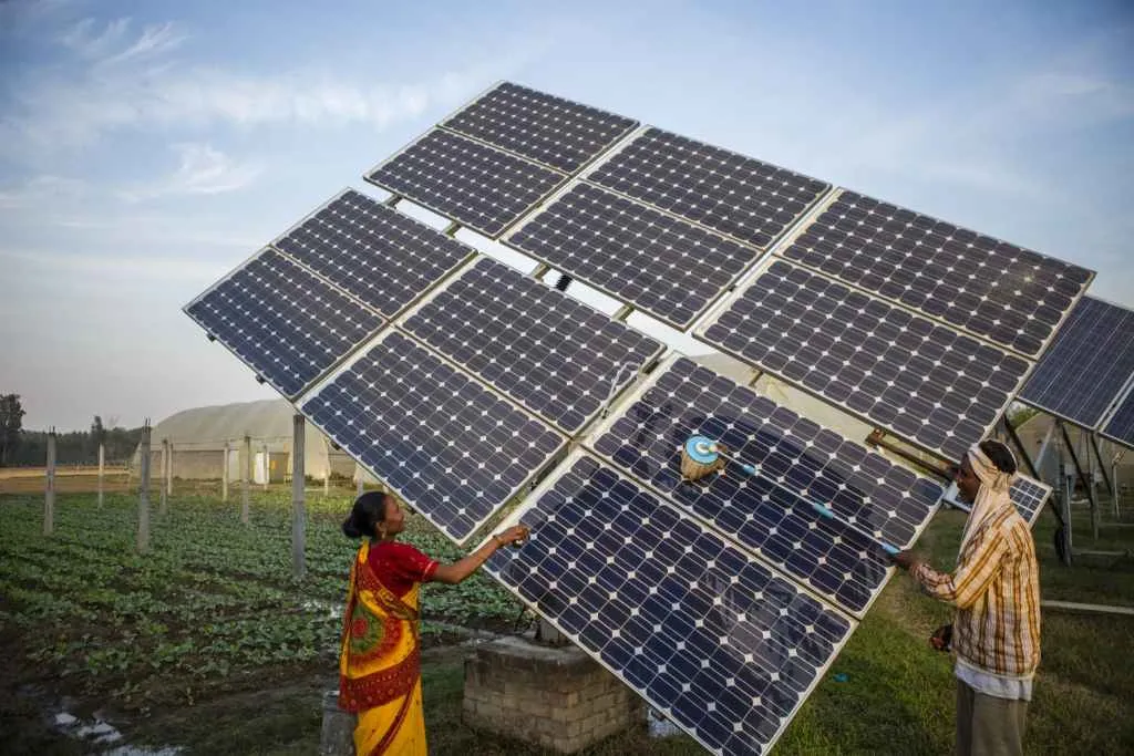 Farm workers clean the solar panels of a solar water pump at the farms in Jagadhri 