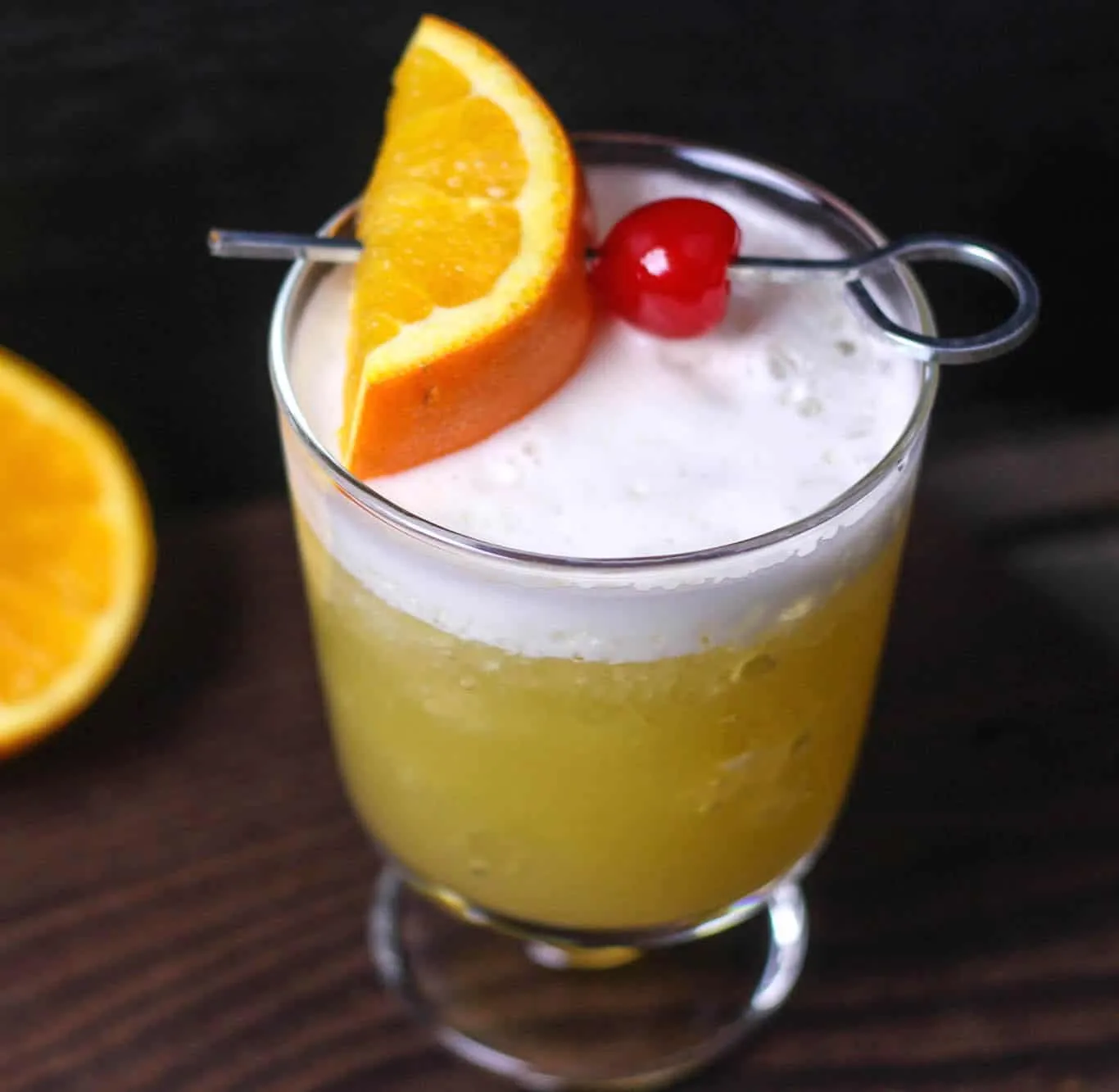 This delicious whiskey sour recipe goes down so easily! Flavored with orange juice and topped with whipped cream and a cherry, it's a tasty cocktail treat.