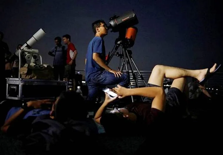 Astronomy enthusiasts prepare their telescopes to see the lunar eclipse at Marina South Pier in Singapore (Source, Reuters)