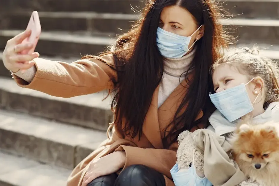 A mother and daughter wearing masks take a selfie outdoors during COVID-19 with their pet dog.