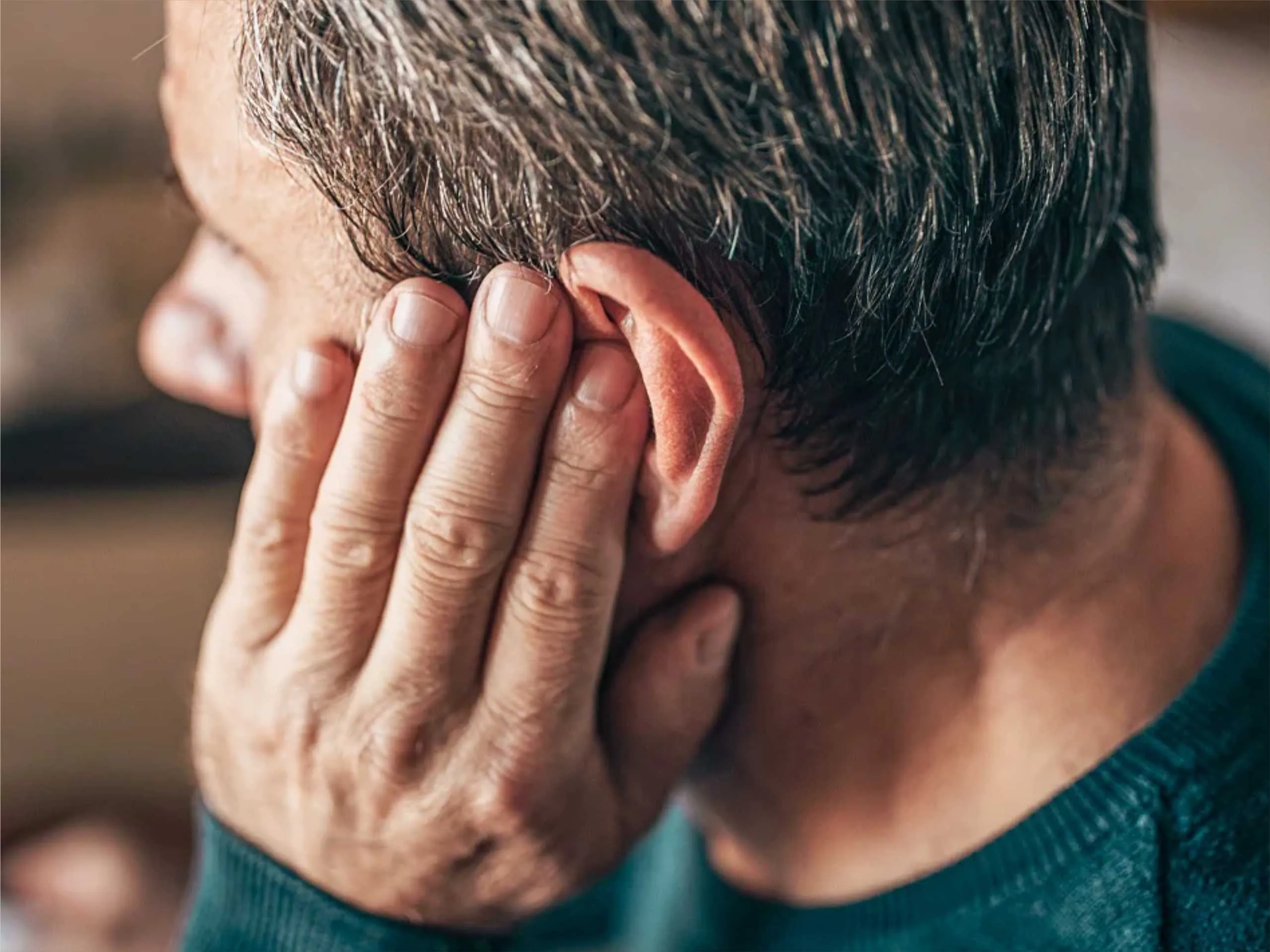 Man closing his ears due to noise pollution