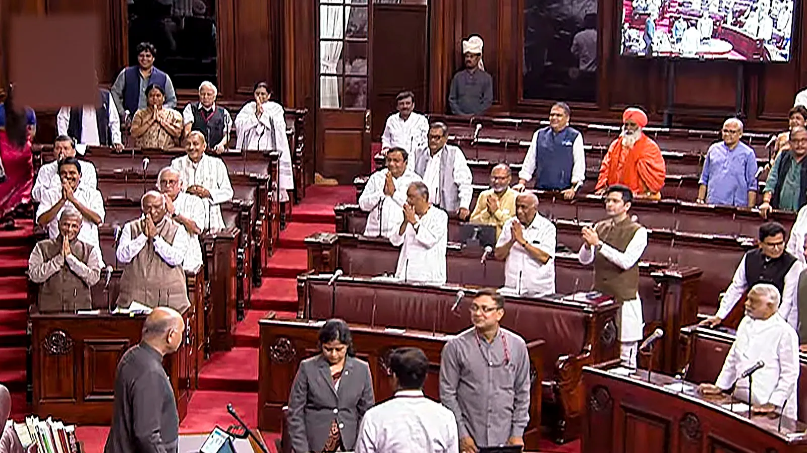 Parliamentarians welcome Rajya Sabha Chairman Jagdeep Dhankhar (unseen) in the House during the Monsoon session of Parliament, in New Delhi