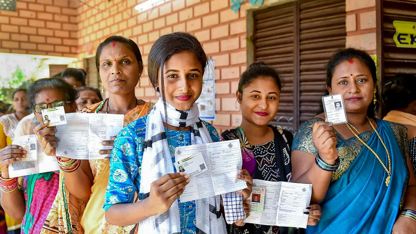 Voters show their identification cards as they wait in a queue at a polling station to cast their votes for the fourth phase of Lok Sabha elections, in Ganjam district of Odisha, Monday, May 13, 2024