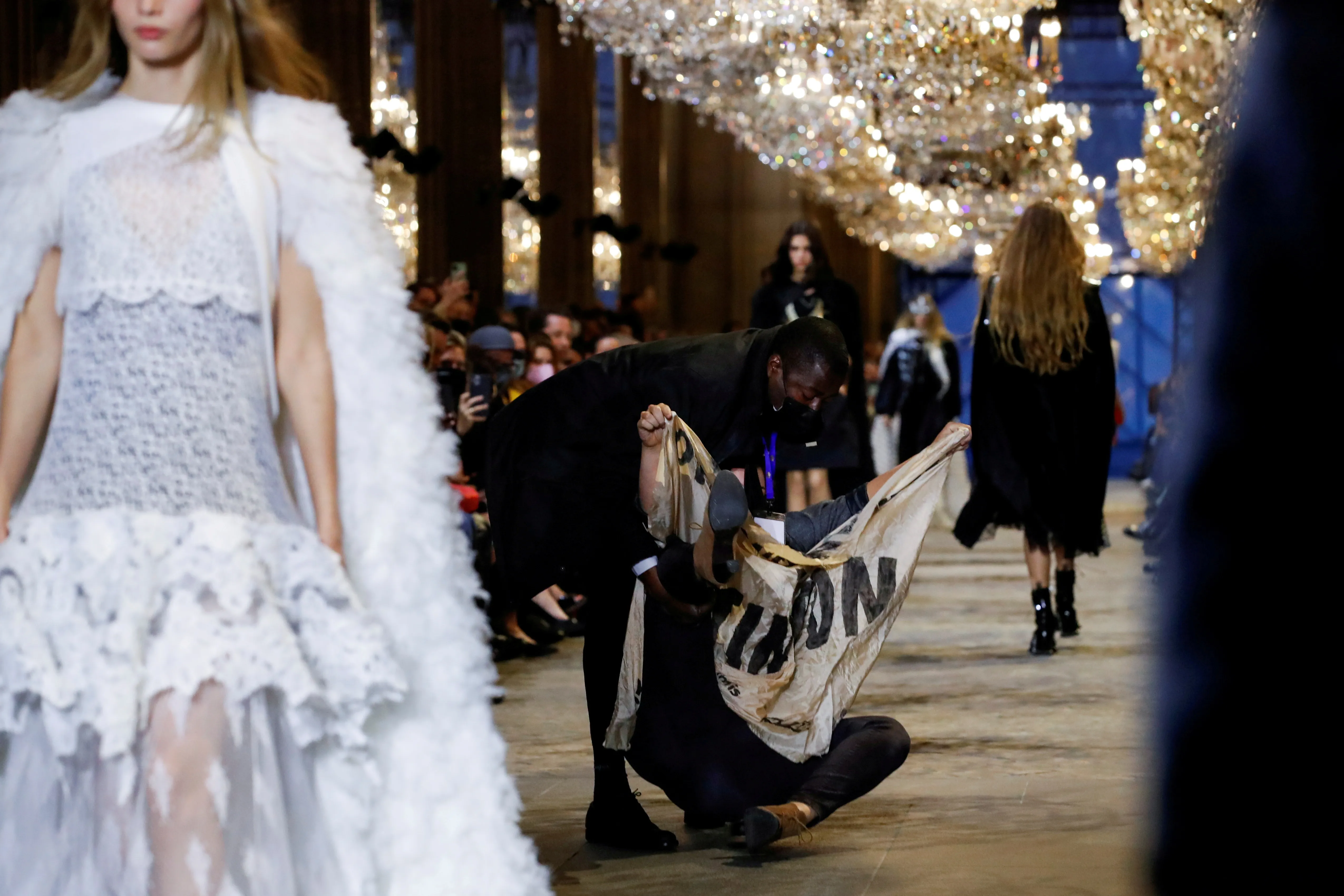 Security personnel remove an activist belonging to the 'Les Amis de la Terre France' or 'Friends of the Earth - France' , who crashed the designer Nicolas Ghesquiere Spring/Summer 2022 women's ready-to-wear collection show for fashion house Louis Vuitton during Paris Fashion Week in Paris, France, October 5, 2021. REUTERS/Gonzalo Fuentes