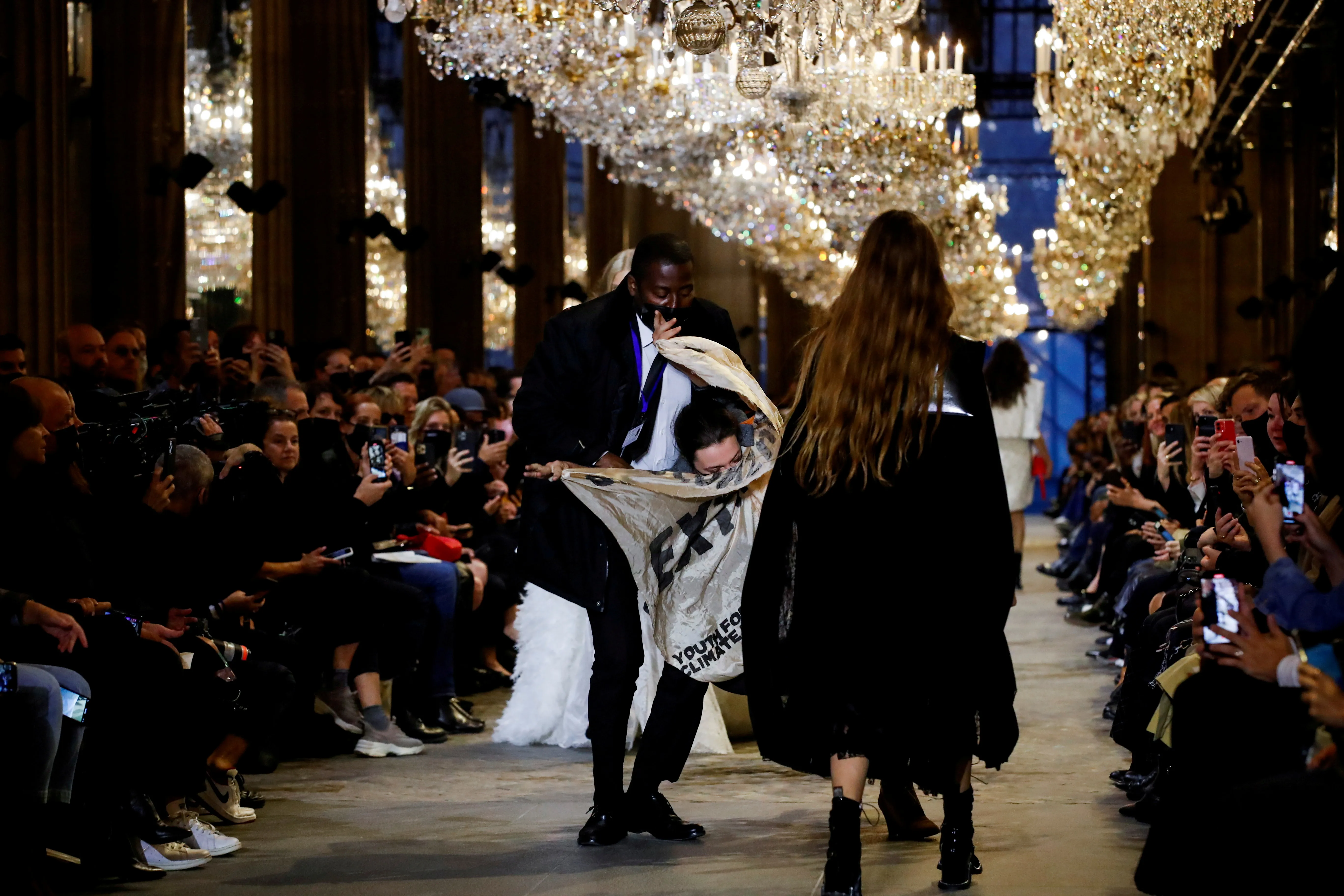 A member of the security personnel removes an activist belonging to the 'Les Amis de la Terre France' or 'Friends of the Earth - France' , who crashed the designer Nicolas Ghesquiere Spring/Summer 2022 women's ready-to-wear collection show for fashion house Louis Vuitton during Paris Fashion Week in Paris, France, October 5, 2021. REUTERS/Gonzalo Fuentes