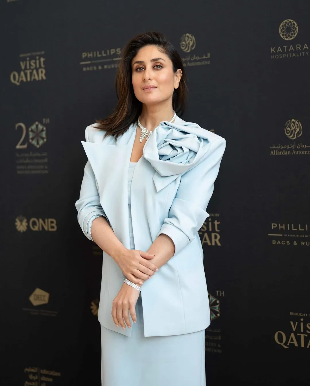 Kareena Kapoor in Qatar at the Doha Jewelry & Watches Exhibition 20th Edition. She is wearing a beautiful light blue suit with a flower design collar.  