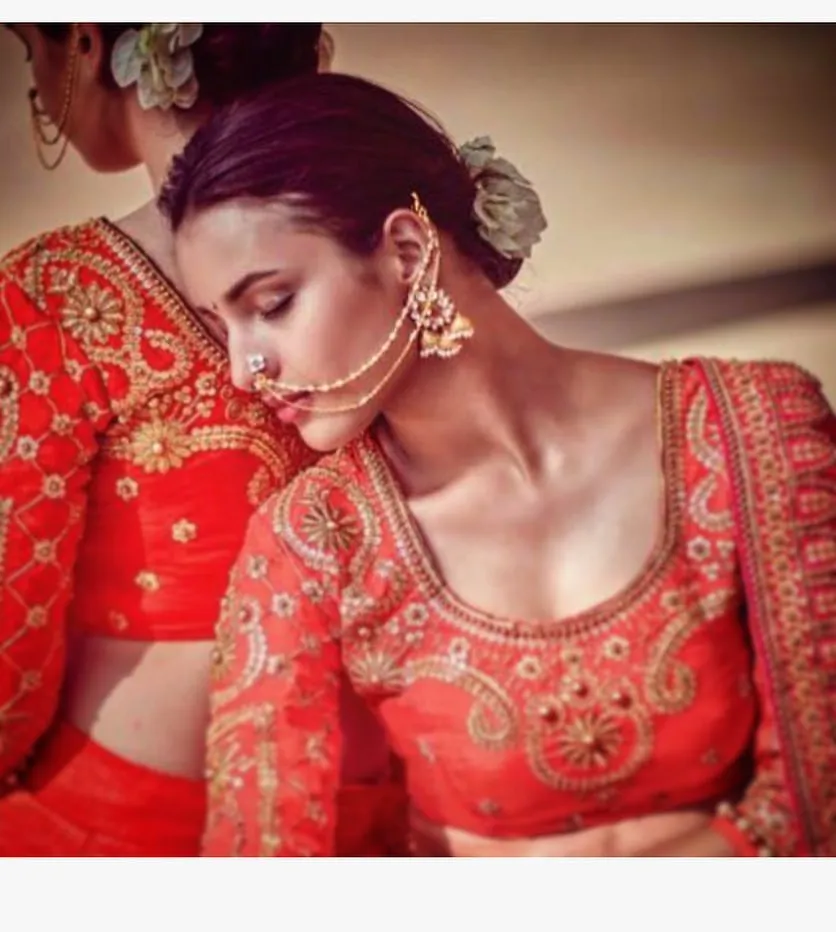 Tripti Dimri in a traditional Indian outfit, featuring a richly embroidered red blouse with golden details. The floral hair accessories and elegant jewelry, including a nath (nose ring), add to the ethnic charm of the.jpg  