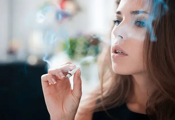 The thoughtful woman smokes a cigarette.