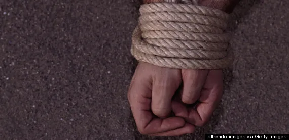 Close-up view of hands bound together with heavy rope