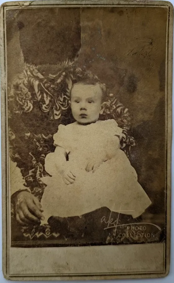 The draped ‘mother’ in this carte-de-visite is probably a man, based on the visible adult hand and sleeve. The head of the adult was removed by a smear on the developing plate. JNO. W. Minner’s City Gallery, Sparta, Illinois. (c. 1862–64) © Andrea Kaston Tange. All images are from the author’s private collection.