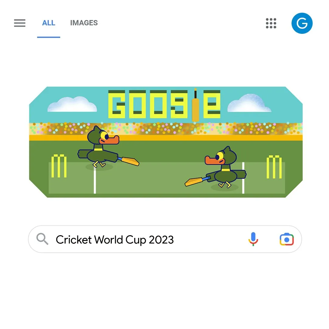 A screenshot of Google Search homepage with the Google Doodle for Cricket World Cup 2023 and the Search bar having the query 'Cricket World Cup 2023' placed below.<br />
The doodle is an illustration of a cricket stadium, with two ducks on the crease<br />
On top of this illustration we have 'Google' written with the 'l' replaced by a cricket bat
