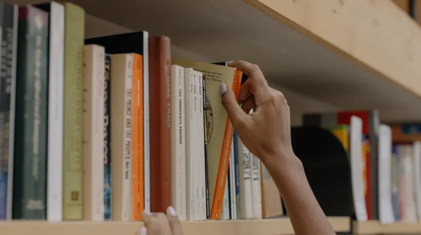 hands picking book from a rack