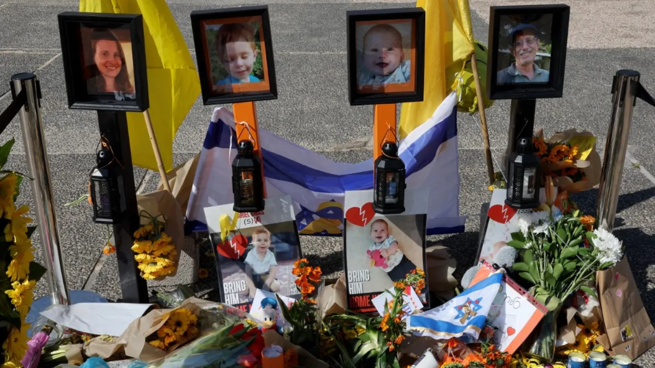  People walk around a makeshift memorial in front of portraits of late Israeli hostages Shiri (L), Ariel (CL), and Kfir (CR) Bibas, as well as Oded Lifshitz (R) at Hostages Square in Tel Aviv on February 25, 2025. Photograph: (AFP) 
