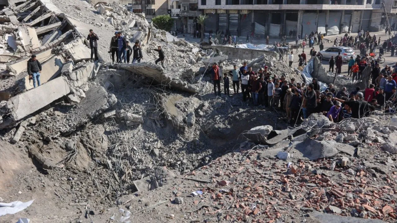  Palestinians inspect a crater at the site of Israeli strikes on a makeshift displacement camp in central Gaza City on March 23, 2025. Photograph: (AFP) 