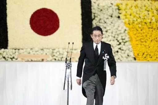 Japan’s Prime Minister Fumio Kishida walks on stage