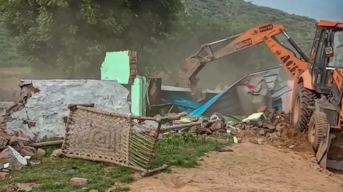 A bulldozer demolishes alleged illegal constructions after orders from the district administration in Nuh district on Friday, Aug. 4