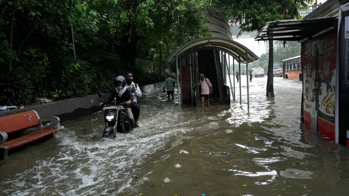 Commuters make their way through the waterlogged ITO road due to the rising water level of Yamuna river following heavy monsoon rains in nearby states, in New Delhi, Friday, July 14