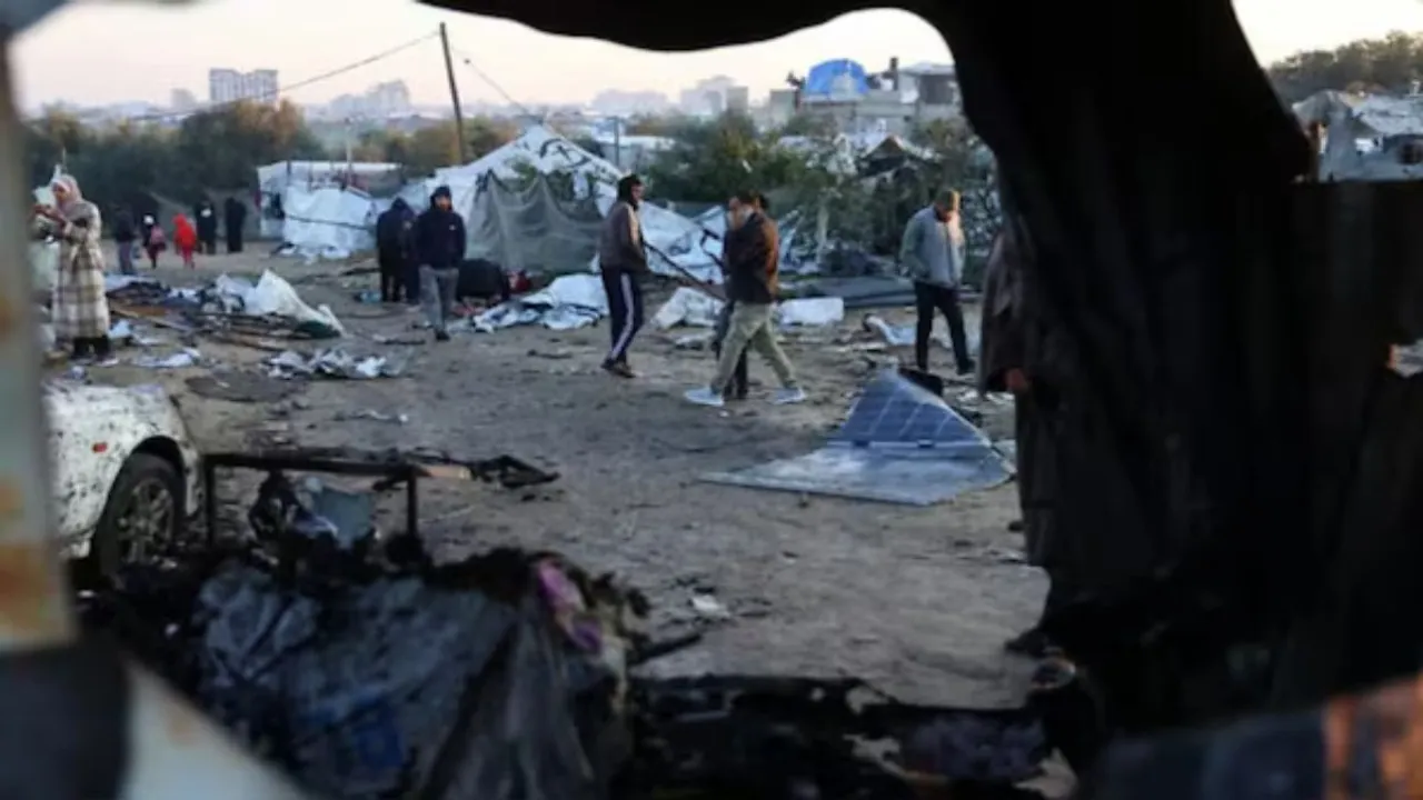  Palestinians walk amid scattered debris of tents on Thursday following an overnight Israeli strike on a makeshift displacement camp in al-Mawasi in the southern Gaza Strip, that reportedly killed at least 11 people, including the chief of the Hamas police chief and his deputy Photograph: (AFP) 