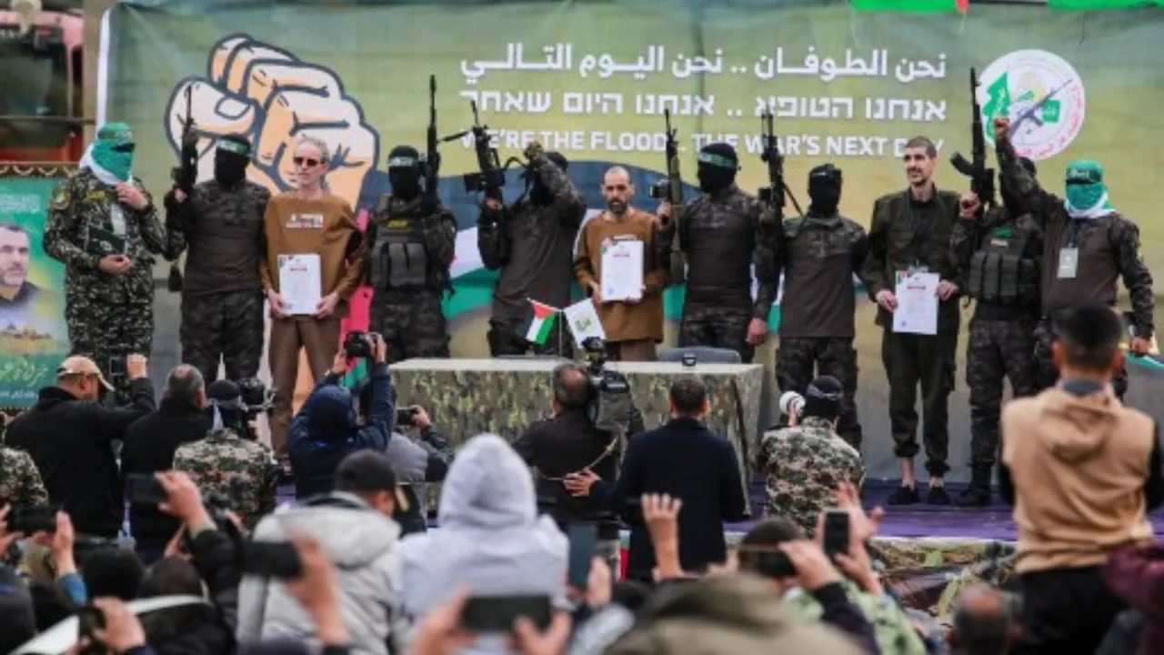  Hamas fighters escort Israeli hostages on a stage before handing them over to a Red Cross team. Photograph: (AFP) 