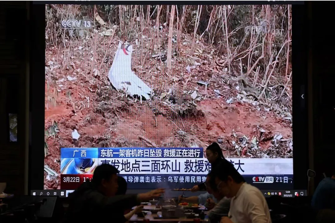  A screen shows news footage of plane debris at the site where a China Eastern Airlines Boeing 737-800 plane flying from Kunming to Guangzhou crashed in Wuzhou of Guangxi Zhuang Autonomous Region, while customers dine at a restaurant in Beijing, China on March 22, 2022 Photograph: (Reuters) 