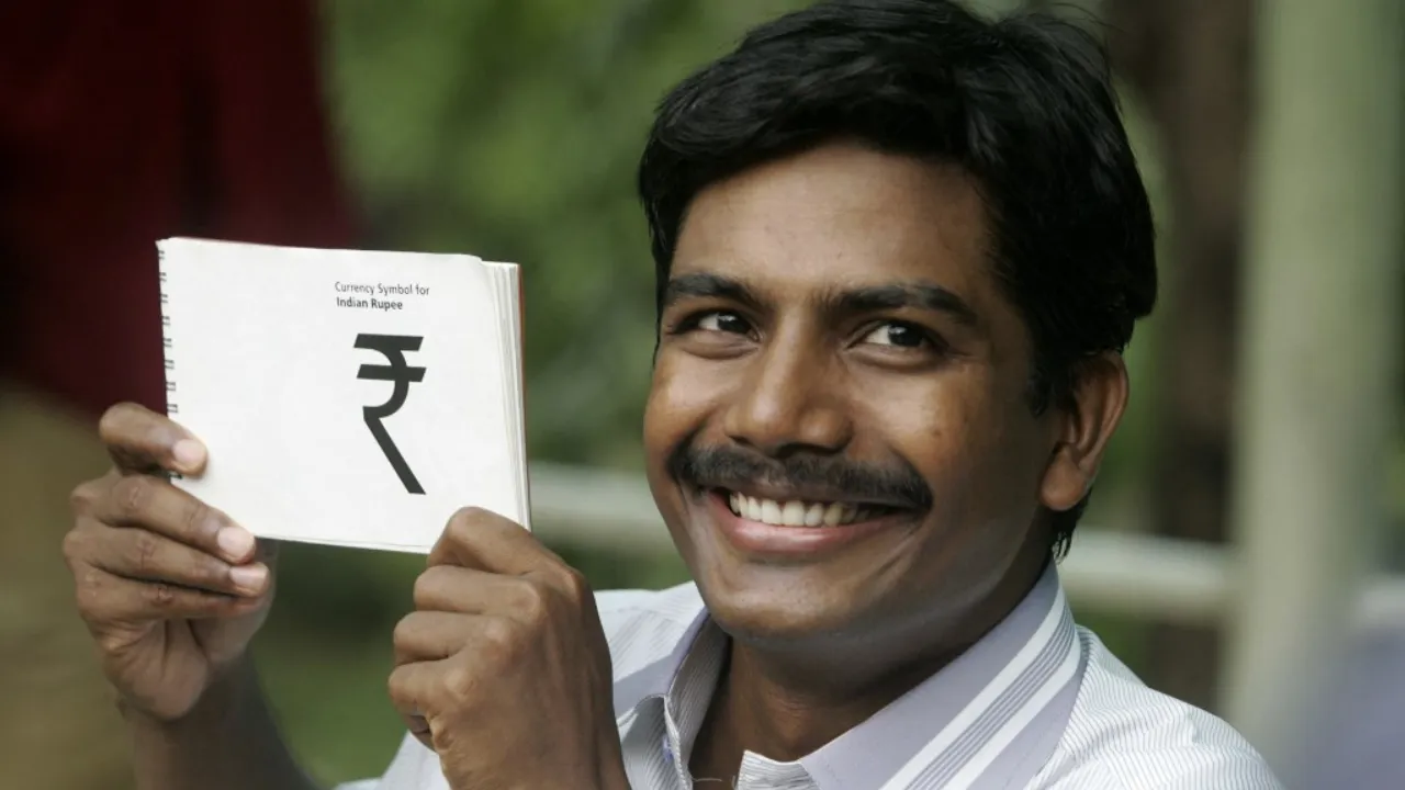  File Photo: Indian scholar D.Udaya Kumar poses holding his winning design for the Indian Rupee symbol in Mumbai on July 15, 2010. Photograph: (AFP) 