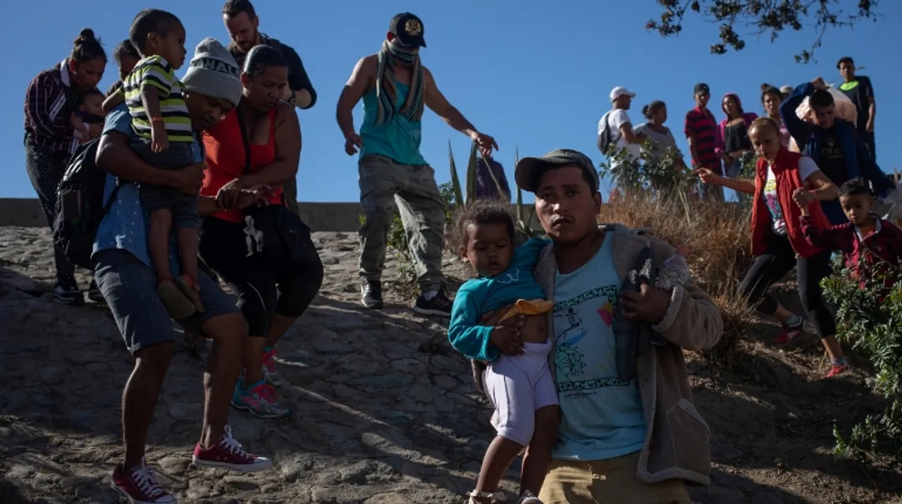  Migrant families, part of a caravan of thousands from Central America, look to cross the border into the United States from Tijuana, Mexico. Photograph:(Reuters) 