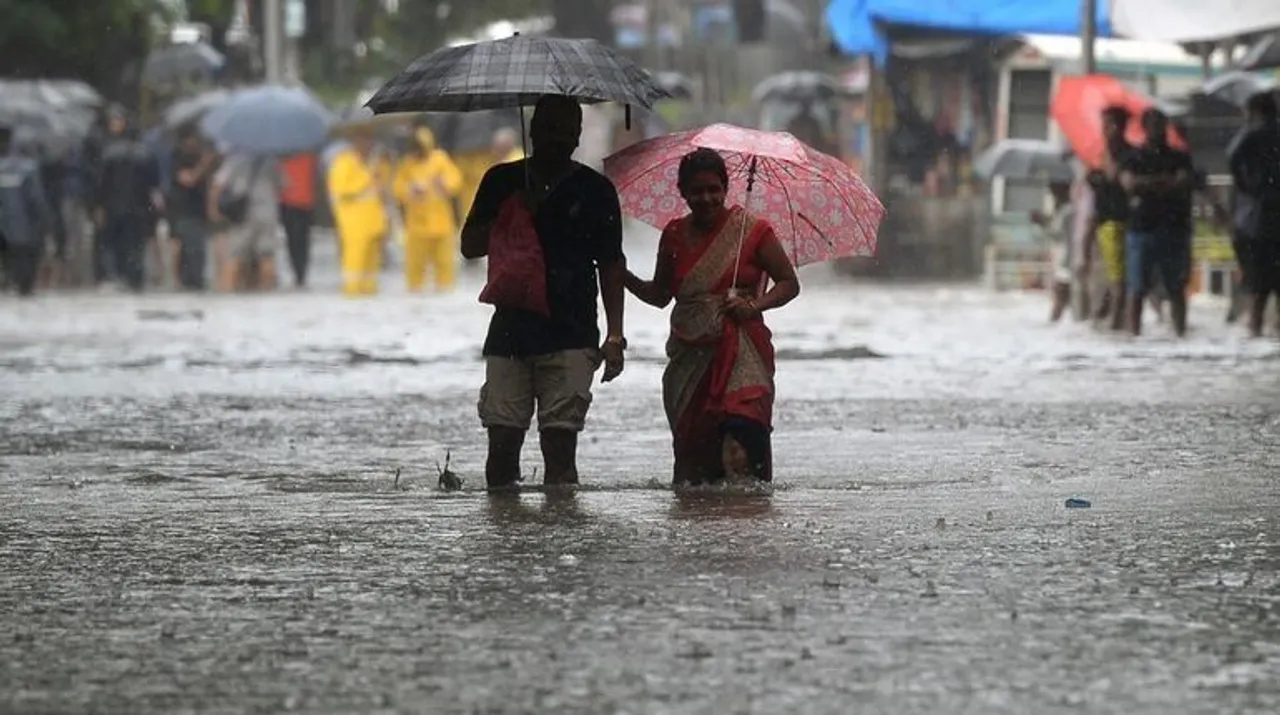  People walk on a flooded road during heavy rain showers Photograph:(AFP) 