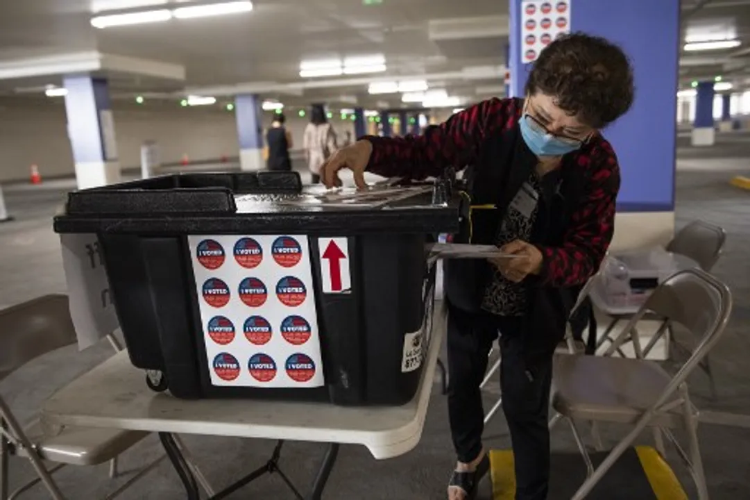  A poll worker helps voters to put their ballot in the Drop-off box at the Beverly Hills City Hall vote center Photograph:(AFP) 