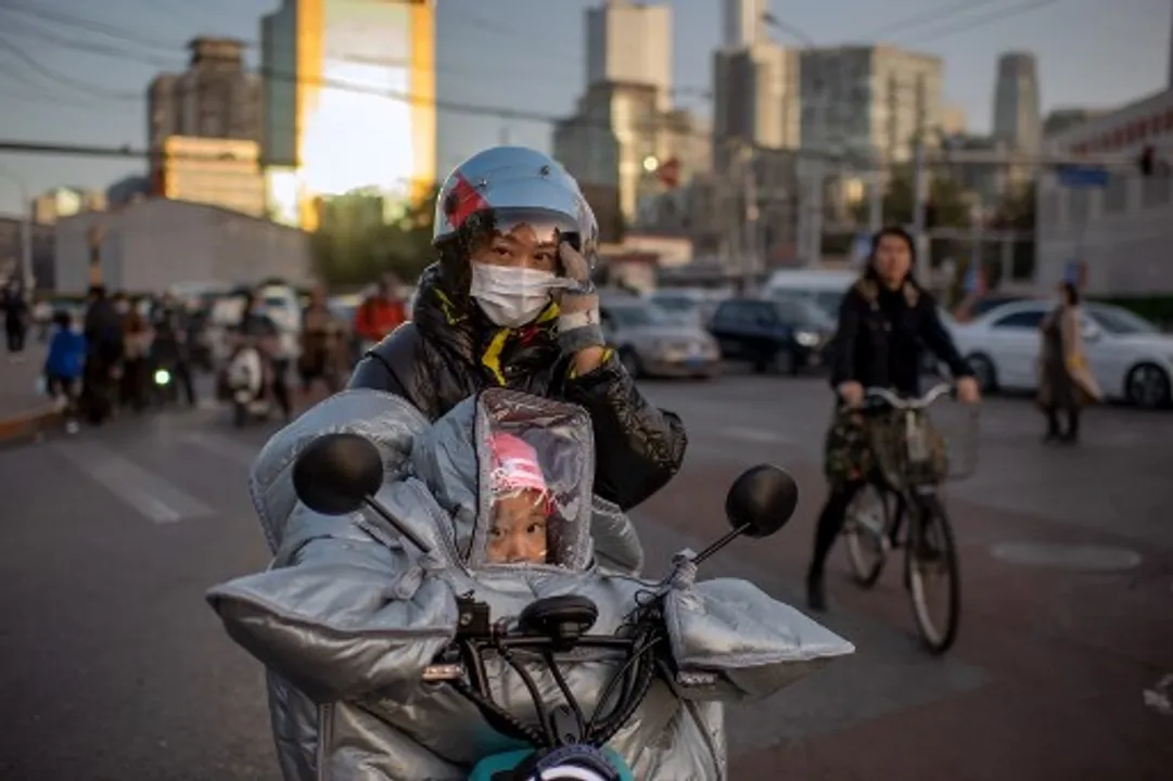  A woman wearing a face mask as a preventive measure against the Covid-19 coronavirus waits to cross a street with her daughter in Beijing Photograph:(AFP) 