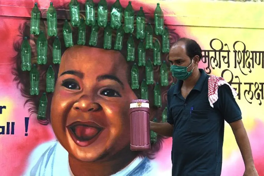  A man wearing a facemask walks past a mural in Mumbai Photograph:(AFP) 