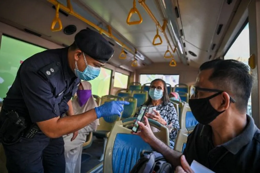  A policeman inspects the travel documents of a passenger on a bus at a roadblock during the nationwide lockdown, amid fears over the spread of coronavirus, in Kuala LumpurÂ  Photograph:(AFP) 