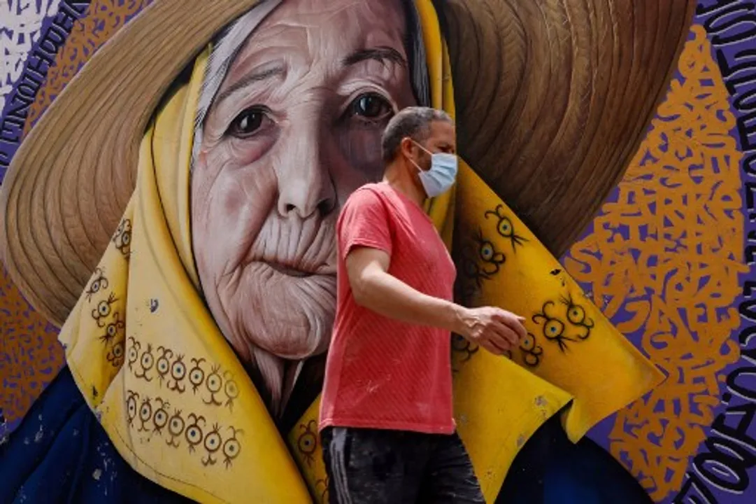  A man wearing a face mask walks past a wall art mural in the Spanish Island of Ibiza  Photograph:(AFP) 