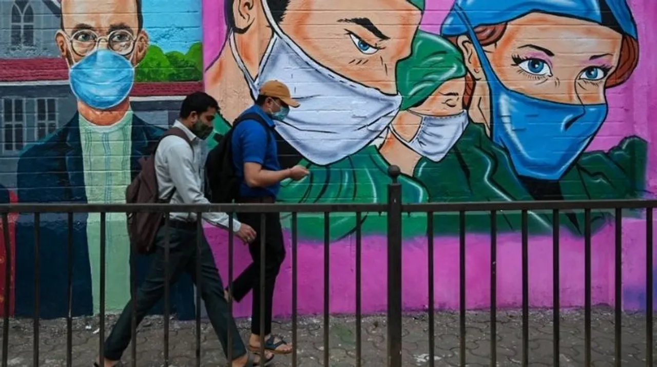  Pedestrians walk past a wall mural depicting health workers to spread awareness about the Covid-19 coronavirus in Mumbai on November 30, 2021. Photograph:(AFP) 