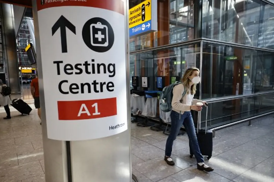  A traveller walks past a sign directing the public to a COVID-19Â testing centre in LondonÂ  Photograph:(AFP) 