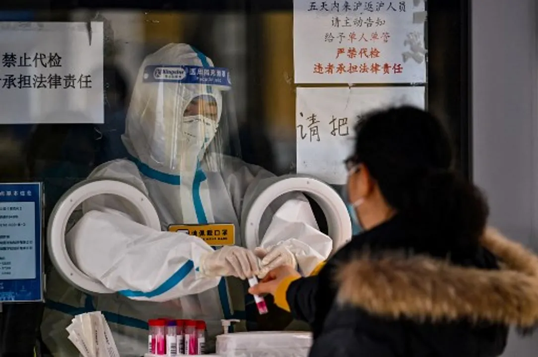  A health worker prepares to take a swab sample from a woman in Shanghai Photograph:(AFP) 
