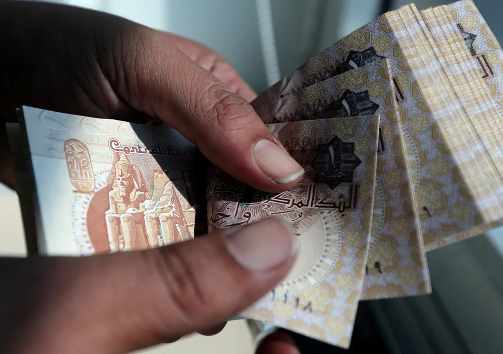  A man counts Egyptian pounds outside a bank in Cairo, Egypt Photograph:(Reuters) 