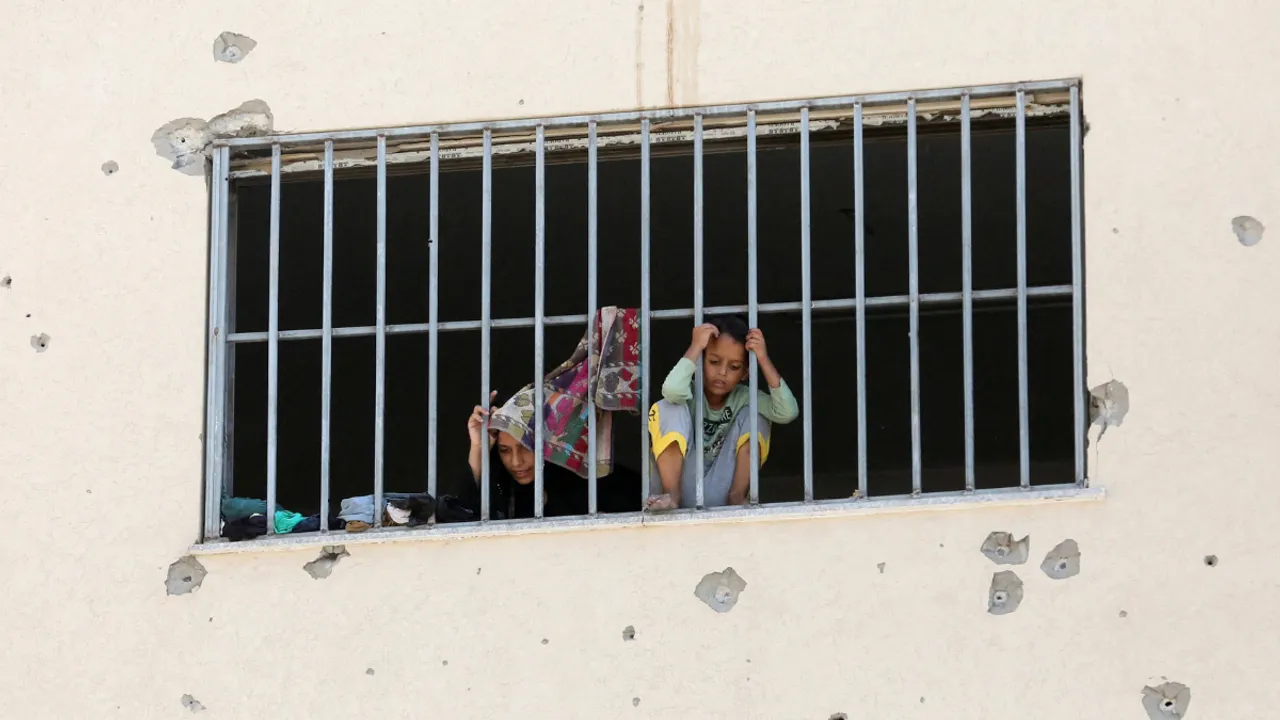  Displaced Palestinians, who fled their houses due to Israeli strikes, look out from a window as they take shelter, amid the ongoing conflict between Israel and Hamas Photograph:(Reuters) 