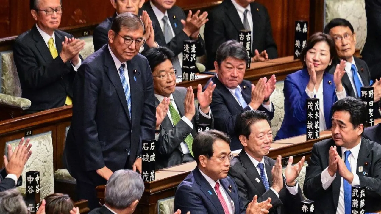   Lawmakers applaud as Japan's Prime Minister Shigeru Ishiba (standing L) is reappointed as leader after the second round of a parliamentary vote to nominate a prime minister following the October 27 general election, during a special session of parliament in Tokyo on November 11, 2024. Photograph:(AFP) 