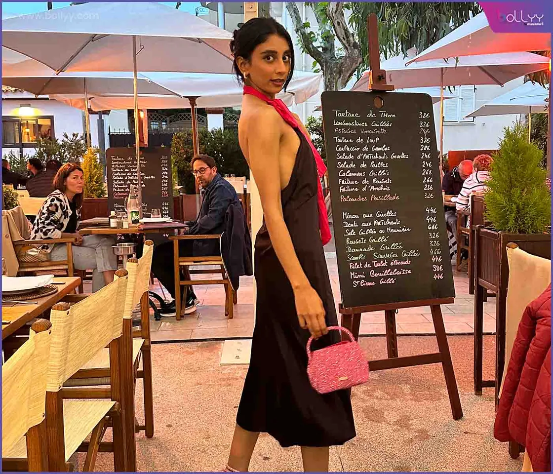 Dolly Singh exudes elegance in a black halter Scotch and Soda dress, pink rhinestone-studded heels and a mini bag complementing the ensemble at Cannes Festival 2023.