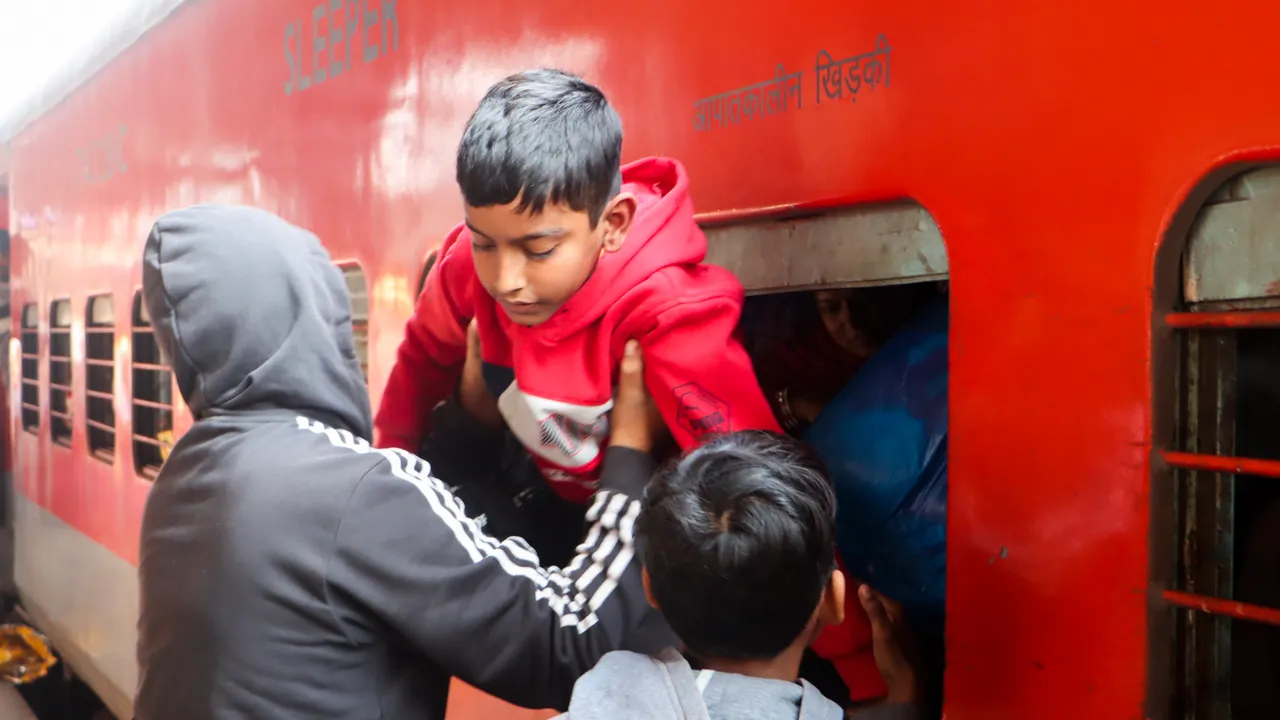 A man tries to board his child through a window of an overcrowded train at the New Delhi railway station on Sunday, Feb. 16, 2025.