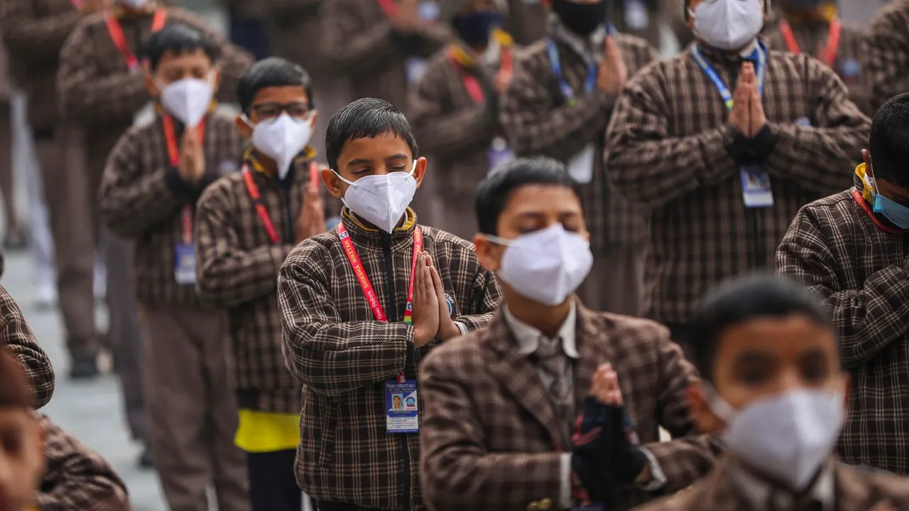 School students wear face masks during prayer amid rise in COVID-19 cases in the country, in Jammu