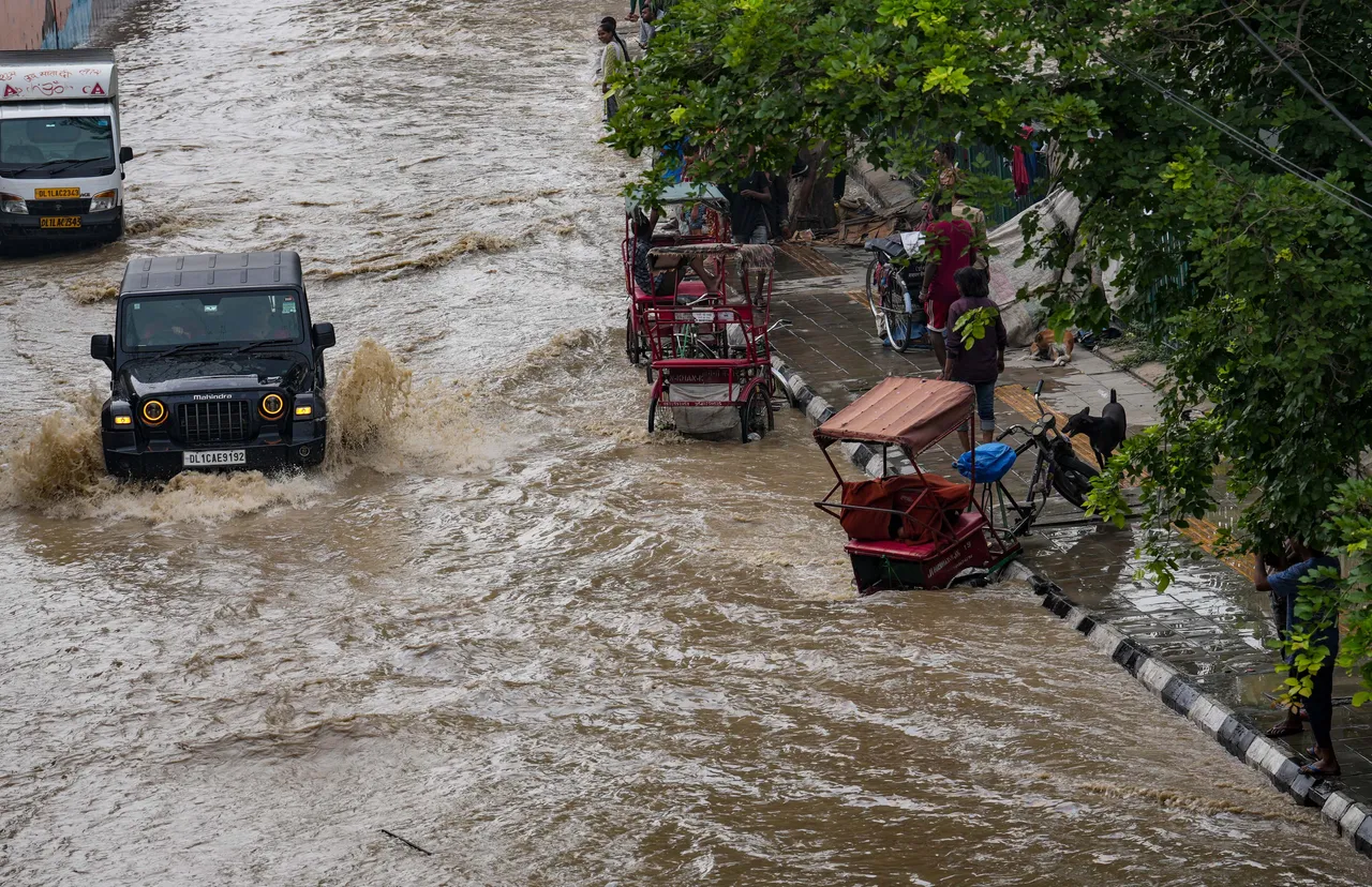 Vehicle move through a flooded road near the Red Fort as the swollen Yamuna river floods low-lying areas, in New Delhi