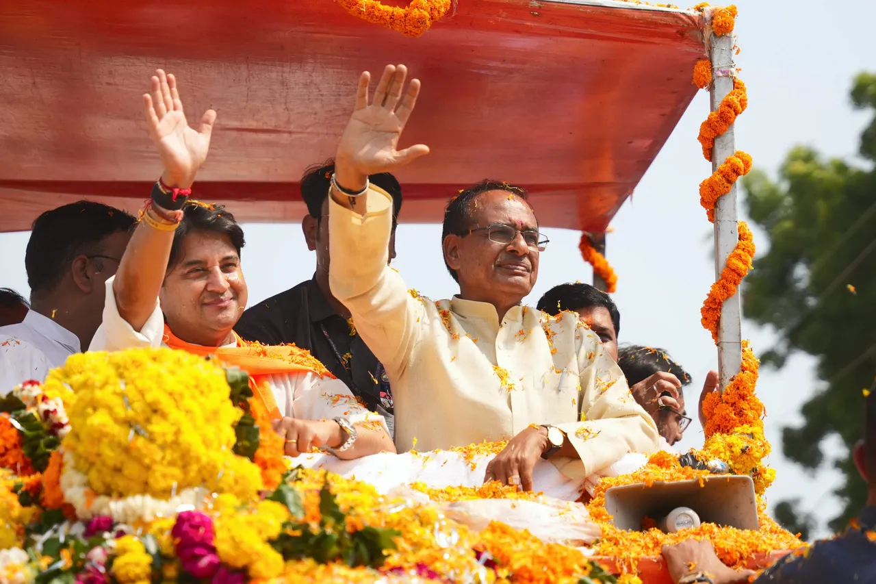Union Minister Jyotiraditya Scindia and Madhya Pradesh Chief Minister Shivraj Singh Chouhan wave at supporters during a roadshow