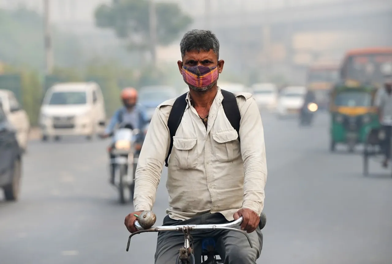 A man wearing a mask rides a bicycle at Anand Vihar amid smog, in New Delhi